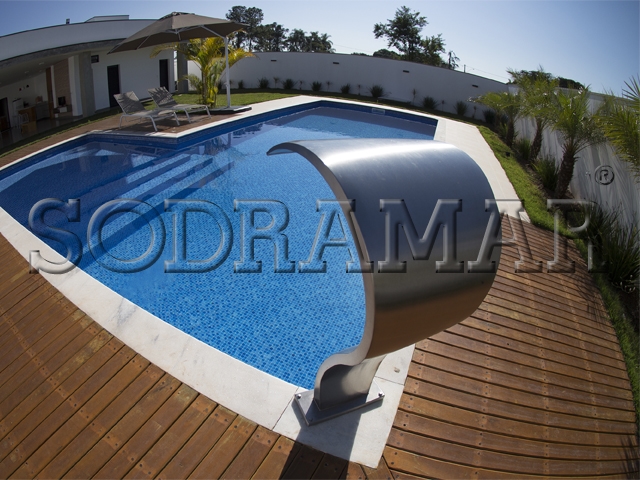 Piscina nos fundos de uma casa com gramado verde.