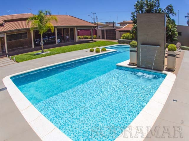 Imagem de uma piscina azul com a água bem limpa e com uma cascata em funcionamento.